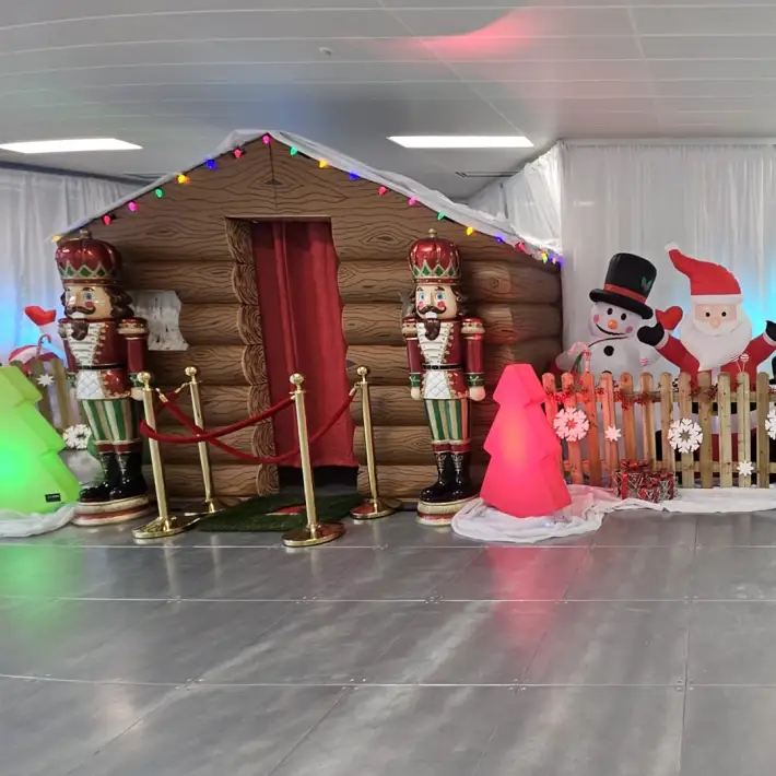 Nutcracker guards, inflatable snowman and Santa outside a decorated grotto at a kids Christmas party in an office setting.