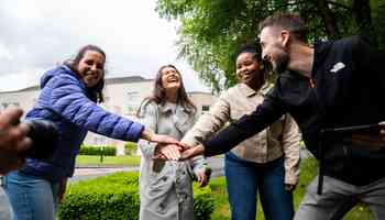 Corporate team building activity in Ireland with colleagues smiling and joining hands outdoors during an August team event.